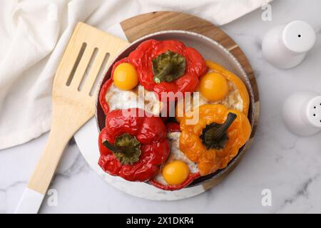 Köstliche gefüllte Paprika mit Spiegeleiern und Spatel auf weißem Marmortisch, Blick von oben Stockfoto