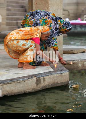 Zwei Pilgerfrauen verehren den Ganges-Fluss in Varanasi mit Weihrauch und einer Flamme. Stockfoto