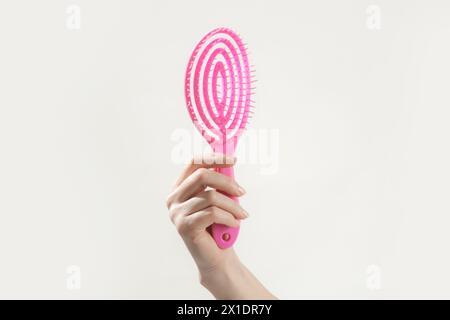 Junge Frau mit rosa Detangler-Haarbürste, Studioaufnahme Stockfoto