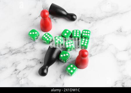 Grüne Würfel und Spielsteine auf weißem Marmortisch, über dem Blick Stockfoto