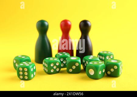 Viele grüne Würfel und Farbspielsteine auf gelbem Hintergrund, Nahaufnahme Stockfoto