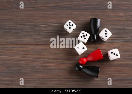 Viele weiße Würfel und Farbspielstücke auf Holztisch, flach gelegt. Leerzeichen für Text Stockfoto