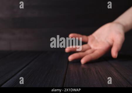 Frau, die Hand über schwarzem Holztisch hält, selektiver Fokus. Leerzeichen für Text Stockfoto