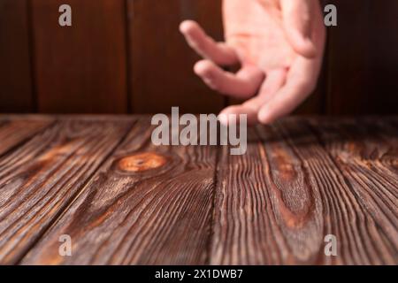 Mann hält Hand über Holztisch, selektiver Fokus. Leerzeichen für Text Stockfoto