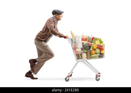 Profilaufnahme eines älteren Rentners, der mit Essen in einem Einkaufswagen auf weißem Hintergrund läuft Stockfoto