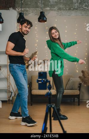 Freunde der Generation Z machen trendige Tanzbewegungen vor einem Kameratelefon. Lebendige junge Menschen, die Inhalte für ihren Vlog in sozialen Medien erstellen. Folgen Stockfoto