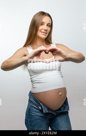 Schwangere junge Frau mit Herzzeichen und einem schönen Lächeln Stockfoto