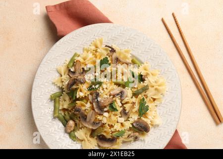 Vegetarische Pasta mit Pilzen, Petersilie, Bohnen und Käse auf orangefarbenem Tisch, Blick von oben Stockfoto