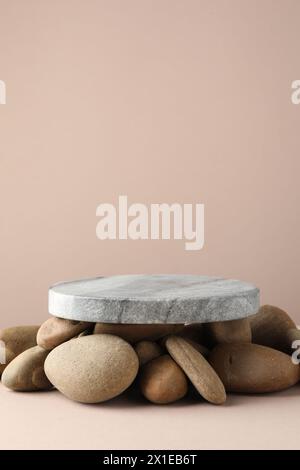 Präsentation für das Produkt. Steinpodium und Kieselsteine auf beigefarbenem Hintergrund. Leerzeichen für Text Stockfoto