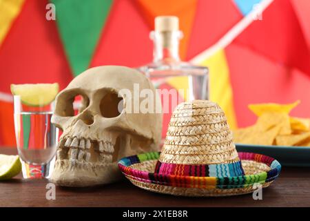 Mexikanischer Sombrero-Hut, menschlicher Schädel und Tequila auf Holztisch Stockfoto