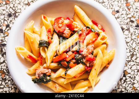 Penne mit herzhafter Salsiccia, saftigen Tomaten und zarten Spinatblättern Stockfoto