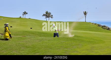 Der Golfspieler schlägt den Ball aus dem Bunker mit einem Golfschläger an einem sonnigen Sommertag. Stockfoto