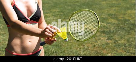 Attraktive sportliche Frau im zweiteiligen Badeanzug, die Badminton im Resort spielt. Shuttlecock und Badmintonschläger in weiblichen Händen. Stockfoto