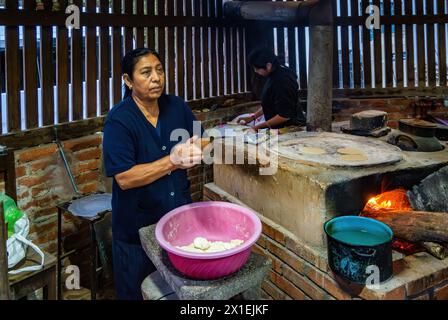 Mutter und Tochter kochen Maistortilla auf einem traditionellen, flachen Herd. Oaxaca, Mexiko. Stockfoto