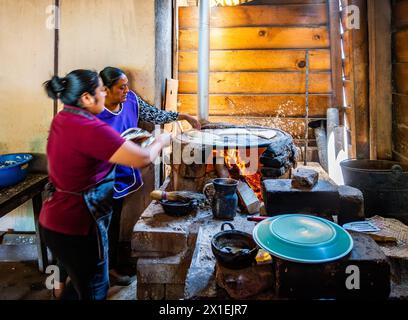 Zwei Frauen kochen Maistortilla auf einem traditionellen, flachen Herd. Oaxaca, Mexiko. Stockfoto