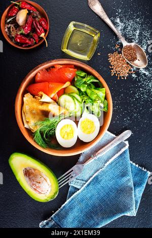 Köstlicher gesunder Brunch - gekochtes Ei, geräucherter Lachs, grüner Salat und herzhafte Pfannkuchen auf dunklem Hintergrund Stockfoto