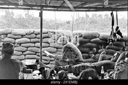 Vietnam war: Ein Berater der Spezialkräfte einer Montagnard-Kampftruppe, erhält die Chance, seine Post in Phey-Shuron zu lesen, einem Lager, das im zentralen Vietnam-Hochland ca. 1964 Stockfoto