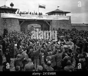 Befreite Gefangene im Konzentrationslager Mauthausen bei Linz, Österreich, heißen Kavalleristen der 11. Panzerdivision willkommen. Das Banner über der Mauer wurde von spanischen Loyalisten-Gefangenen CA. Mai 1945 Stockfoto