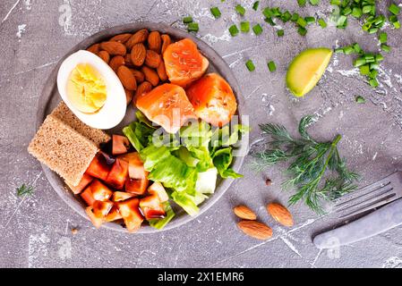Salat mit Lachs, gekochtem Ei, Bohnen, Tomaten und Mandelnüssen. Stockfoto