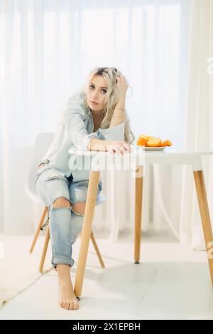 Eine Frau sitzt an einem Tisch mit einem Teller Persimmonen vor sich. Stockfoto