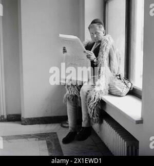 Die Sozialistische Republik Rumänien in den 1970er Jahren Schäferhund trägt einen traditionellen warmen Wollmantel und Hut, der eine Zeitung liest, während er in einem Regierungsbüro wartet. Stockfoto