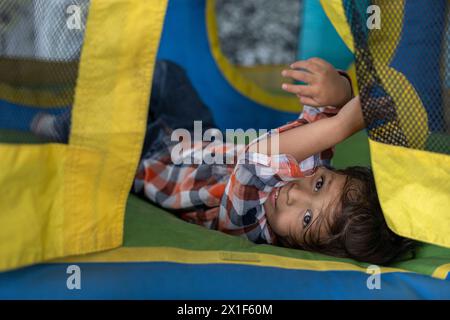 Lateinamerikanischer Junge hat Spaß in Hüpfburgen Stockfoto