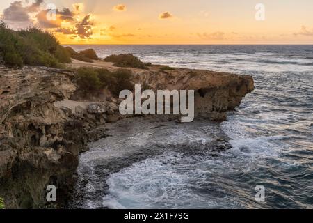 Die Sonne geht langsam über zerklüftete Klippen auf und trifft auf das raue türkisfarbene Wasser des Pazifischen Ozeans entlang des Mahaulepu Heritage Trail in Koloa, Hawaii Stockfoto