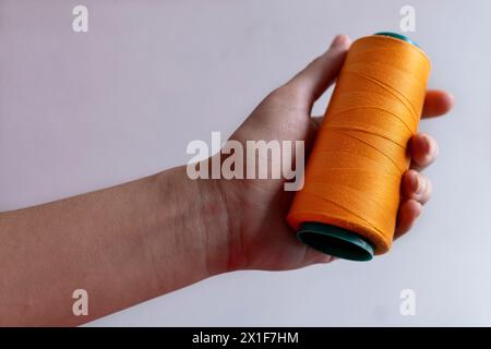 Hände einer lateinamerikanischen Schneiderin, die eine Fadenspule hält. Stockfoto