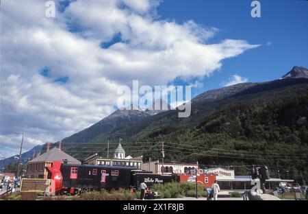 Eine alte schwarze Dampfeisenbahn der White Pass Railway im Zentrum der alaskischen Stadt skagway, Berge und blauer Himmel im Hintergrund Stockfoto