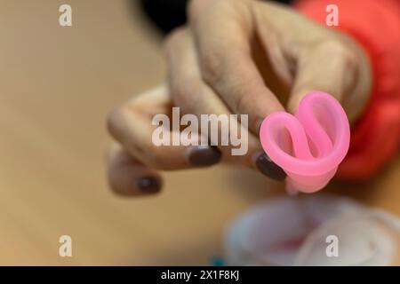 Die Hand des Arztes hält den Menstruationsbecher und zeigt, wie er richtig eingesetzt wird. Stockfoto