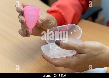 Die Hand des Arztes hält die Menstruationsschale. Gynäkologie und Gesundheitskonzept. Stockfoto