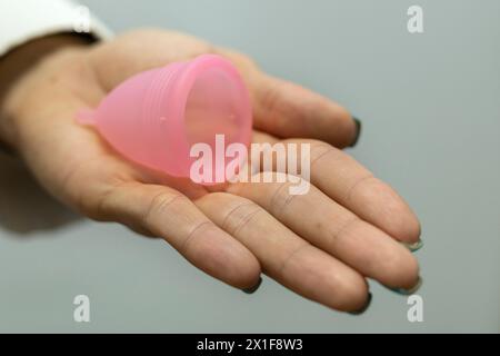 Die Hand des Doktors hält einen Menstruationsbecher an ihrer Hand. Gynäkologie und Gesundheitskonzept. Stockfoto