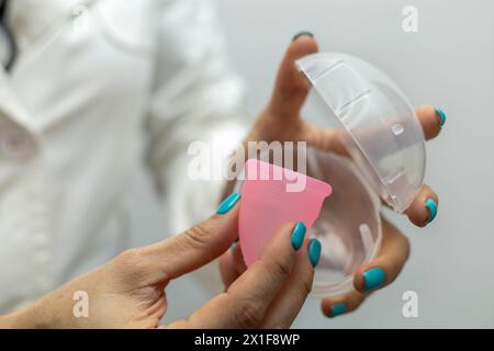 Die Hand des Arztes hält die Menstruationsschale. Gynäkologie und Gesundheitskonzept. Stockfoto