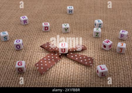 Ein Band und zerstreute Würfel - große Alphabet Würfel auf eine strukturierte Oberfläche in der Anzeige Stockfoto