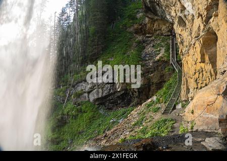 Wasserfall von einer hohen Klippe. Wasser fließt nach unten. Wasserströme krachen auf Felsen und Felsbrocken. Stürmischer Wasserstrahl spritzt. Stockfoto