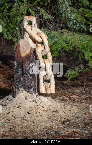 Aus einem Baumstumpf wird eine Kette mit Sägemehl auf dem Boden geschnitzt. Die Szene ist friedlich und ruhig. Stockfoto