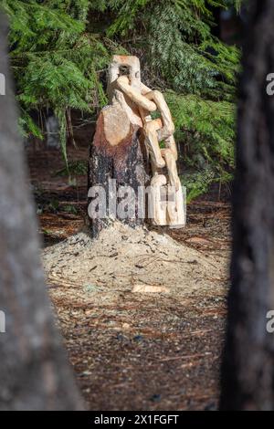 Aus einem Baumstumpf wird eine Kette mit Sägemehl auf dem Boden geschnitzt. Die Szene ist friedlich und ruhig. Stockfoto