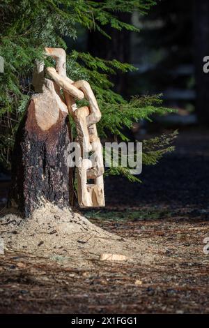 Aus einem Baumstumpf wird eine Kette mit Sägemehl auf dem Boden geschnitzt. Die Szene ist friedlich und ruhig. Stockfoto