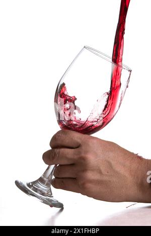 Action-Shoot, der Rotwein in ein Glas über einem weißen Hintergrund gießt Stockfoto