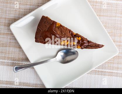 Süßes, zartes dreieckiges Stück Schokoladen-Nuss-Kuchen, mit flüssiger Schokolade gefüllt, auf Teller serviert Stockfoto