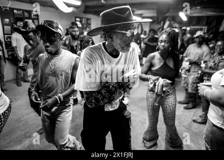 Shelby, North Carolina, USA. August 2023. Ein Cowboy hält sich während eines Treffens und Begrüßens im „BOOM-BOOM Room“ in der Eröffnungsnacht des Ebony Horseman Trail Ride Shelby North Carolina an seinem Glas Mondschein fest. Mindestens 800 Reiter nehmen an dem Trail Ride Teil und über 25.000 Zuschauer besuchten das Rodeo. (Kreditbild: © Brian Branch Price/ZUMA Press Wire) NUR REDAKTIONELLE VERWENDUNG! Nicht für kommerzielle ZWECKE! Stockfoto