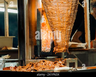 Horizontaler niedriger Nahbereich, der traditionelles Trompo al Pastor Street Taco Schweinefleisch auf Spieß mit Flammen in Mexiko nachts grillt. Stockfoto