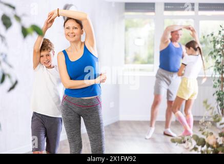 Aktiver Schuljunge, der mit ihrer sportlichen Mutter mittleren Alters im Tanzsaal während des Familientrainings Tanzübungen macht Stockfoto