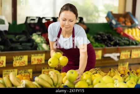 Verkäuferin, die im Supermarkt arbeitet und Äpfel auf der Theke verteilt Stockfoto