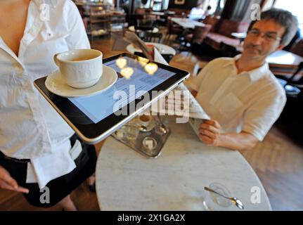 Am Freitag, den 23. Juli 2010, wurde Apple iPad in Österreich auf den Markt gebracht. Im Bild: Zwei Männer sitzen in einem Café, lesen eine Zeitung und arbeiten mit einem iPad - 20100723 PD0380 - Rechteinfo: Rights Managed (RM) Stockfoto