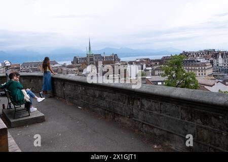 Touristen auf dem Place de la Cathedrale mit Blick auf eine Stadtlandschaft von Gebäuden, den Kirchturm der reformierten Kirche Saint-Francois, den Genfer See und Stockfoto