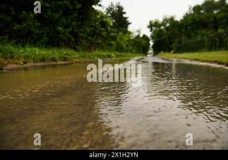 Wasser fließt auf der Straße nach Sommerregen Stockfoto