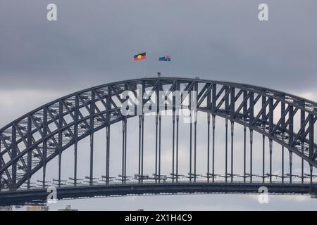 Die berühmte Sydney Harbour Bridge, die Flaggen der Aborigines und australiens, die auf dem Gipfel fliegen, die Menschen, die den Bogen vom Brückenkletterausflug hinunterlaufen, Sydney, NSW Stockfoto