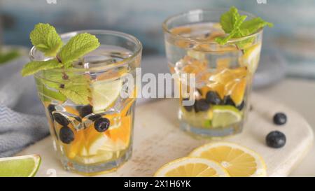 Sommerliche gesunde Cocktails aus Zitruswasser, Limonaden oder Mojitos, mit Limone Zitronenorange Blaubeeren und Minze, Diät Entgiftungsgetränke, in Gläsern Stockfoto