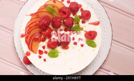 Käsekuchen mit frischen Himbeeren, Pflaumen und Minzblättern. Stockfoto